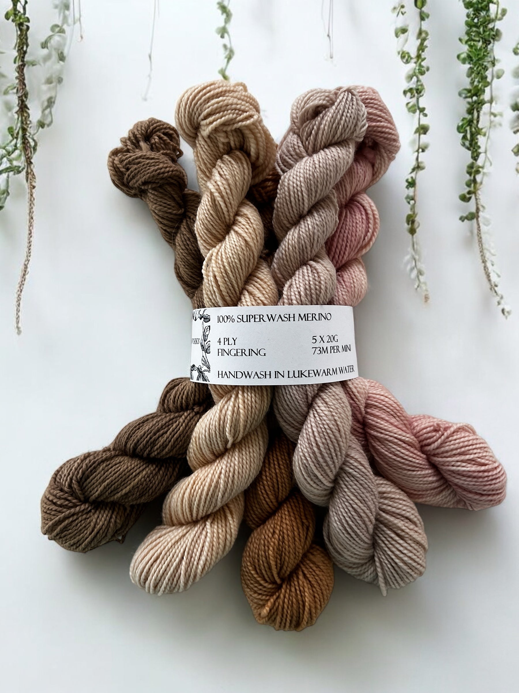 Five mini skeins of naturally dyed merino in coffee, rosy sand, peanut brown, oyster pink-grey and pale pink held together with a yarn label